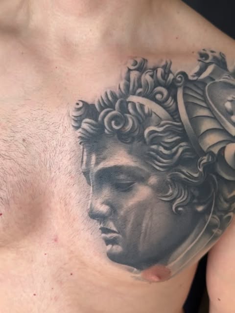 Tatuaje de retrato de estilo realismo con detalle de armadura, trabajo de Alma Mater Tattoo Studio
